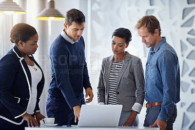 Buy stock photo Shot of a group of coworkers working together on a laptop in an office