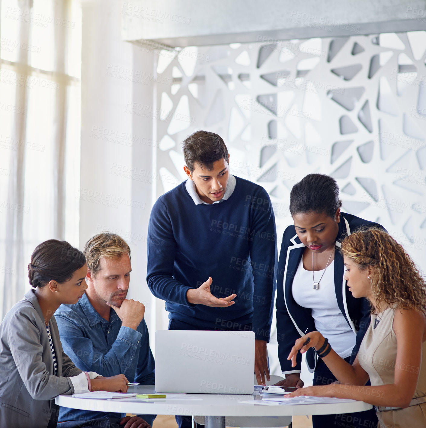 Buy stock photo Shot of a group of coworkers working together on a laptop in an office