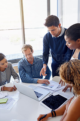 Buy stock photo Shot of a group of coworkers working together on a laptop in an office
