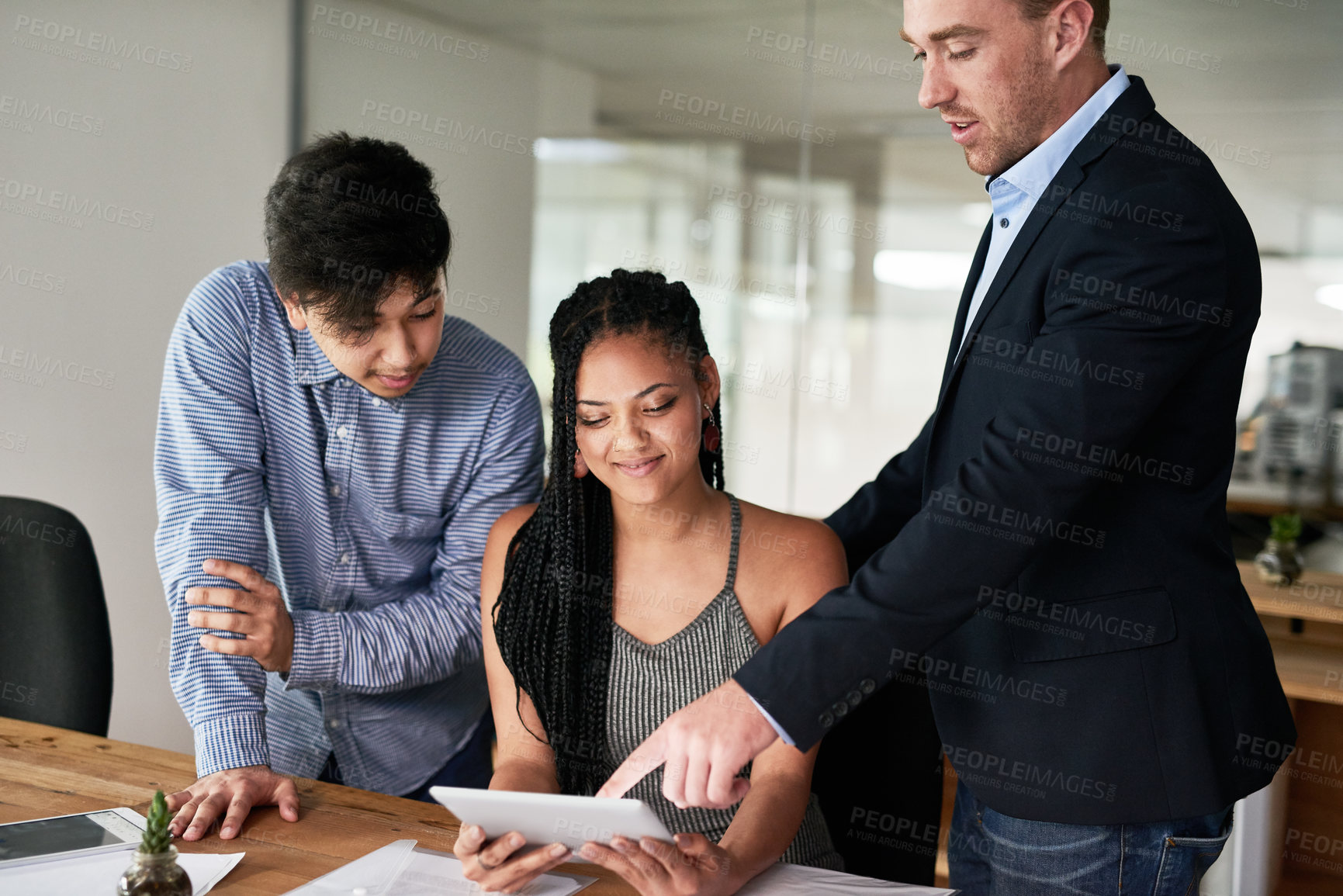 Buy stock photo Shot of a group of colleagues having a brainstorming session with a digital tablet in a modern office