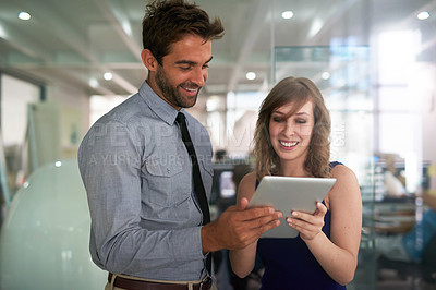 Buy stock photo Shot of two colleagues using a digital tablet together in an office