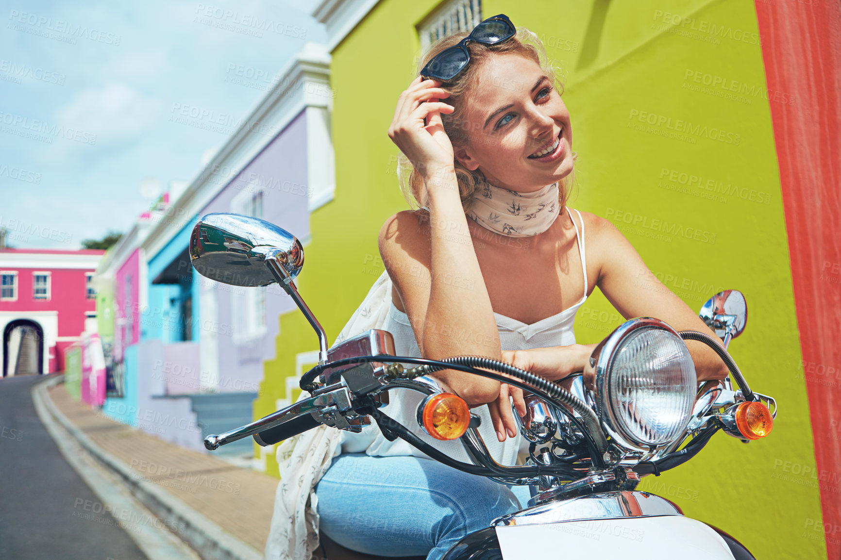 Buy stock photo Shot of a young woman riding a scooter through colorful city streets