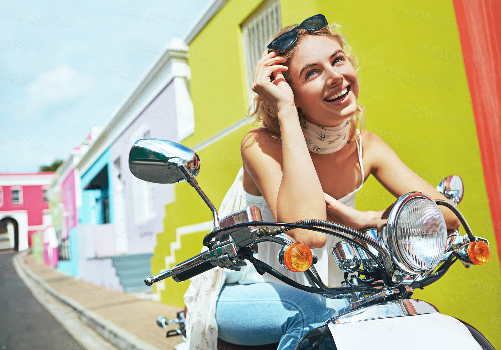 Buy stock photo Shot of a young woman riding a scooter through colorful city streets