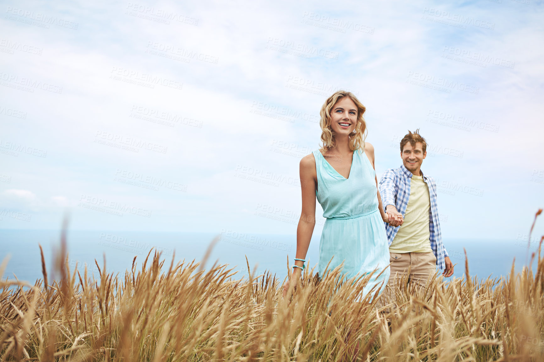 Buy stock photo Shot of a young couple in a field on a sunny day