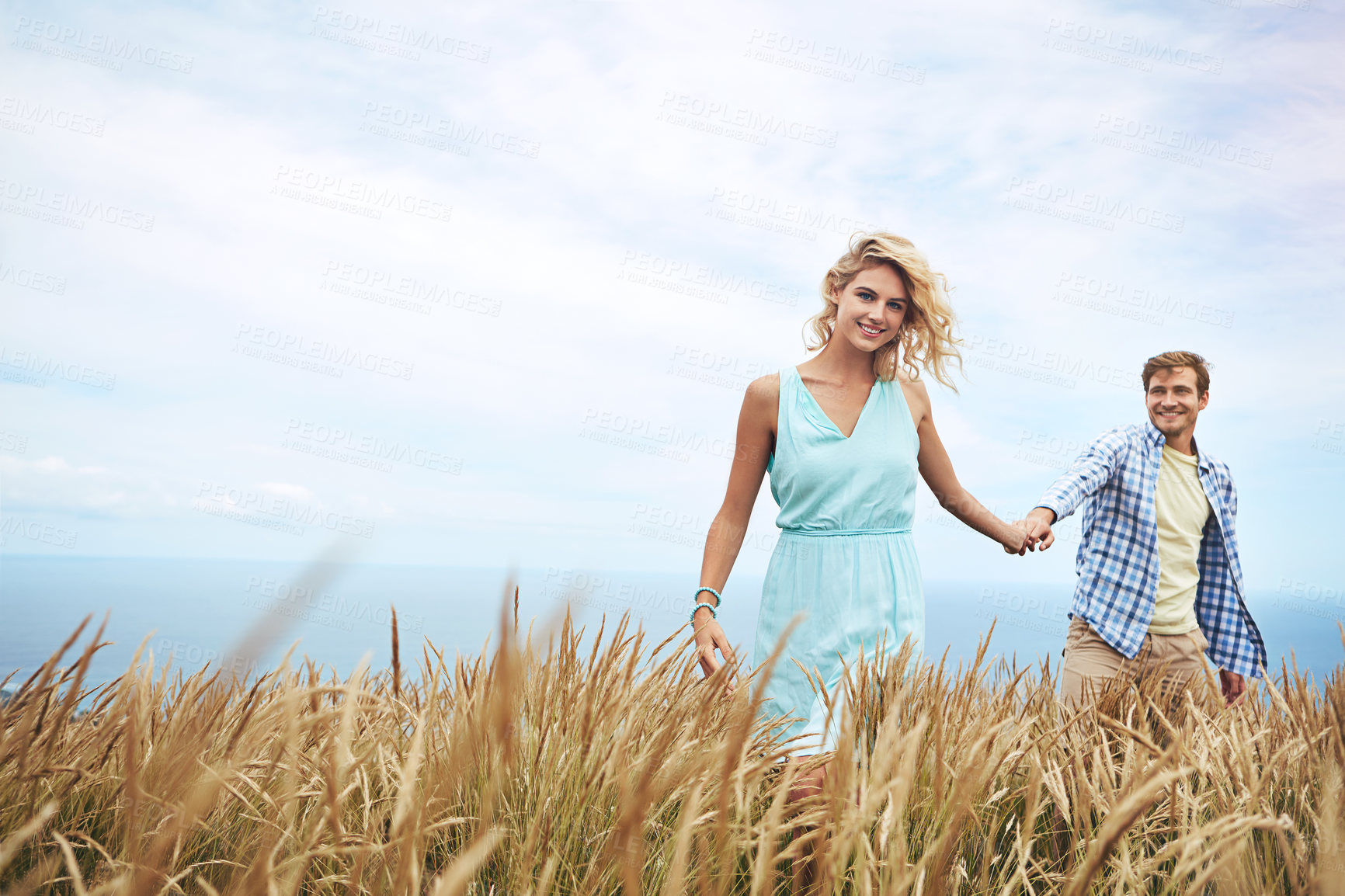 Buy stock photo Shot of a young couple in a field on a sunny day