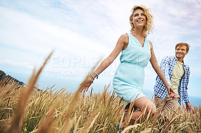 Buy stock photo Shot of a young couple in a field on a sunny day