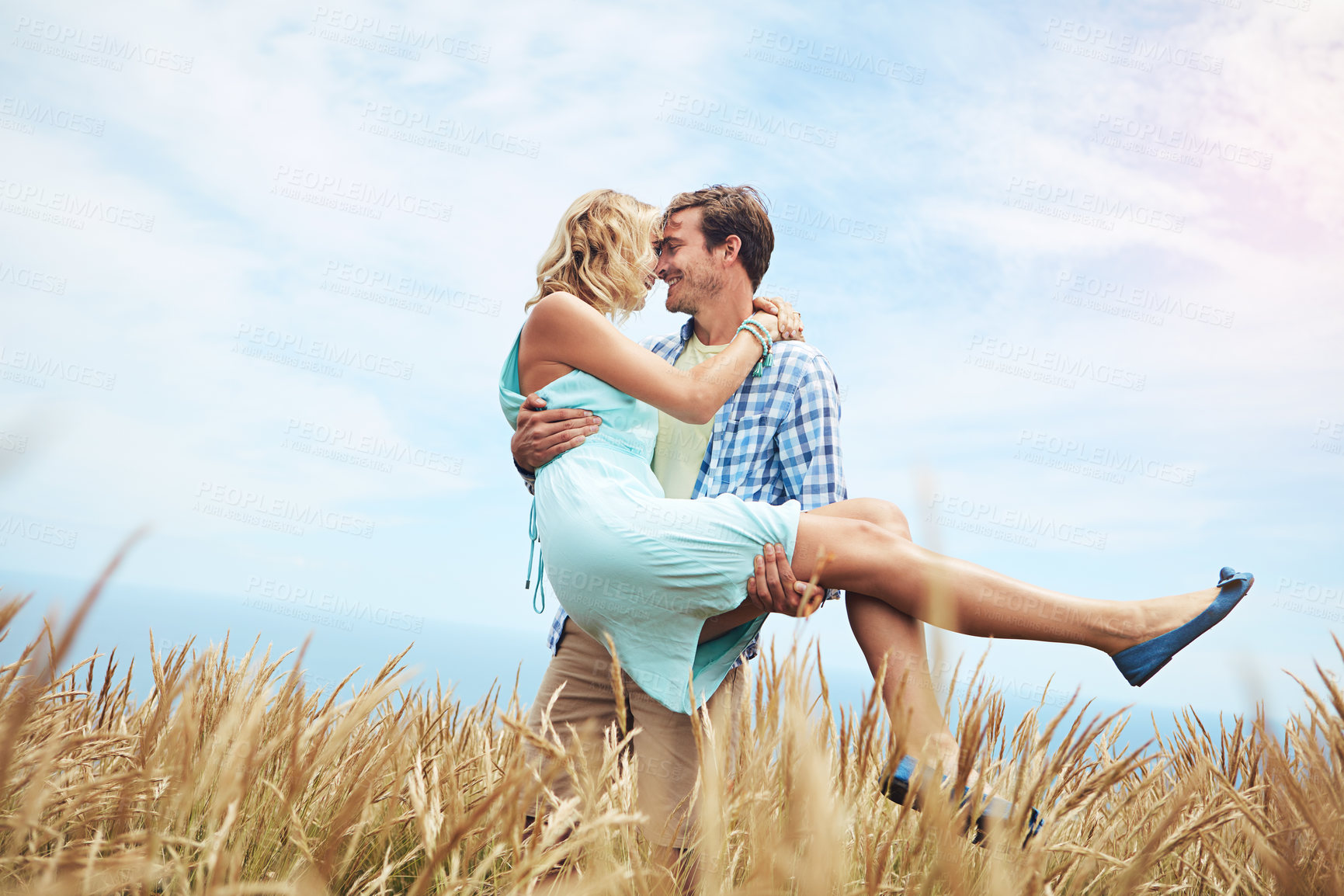 Buy stock photo Shot of a young couple in a field on a sunny day