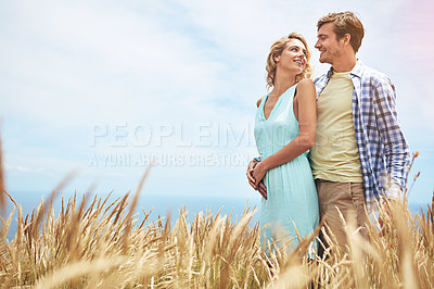 Buy stock photo Shot of a young couple in a field on a sunny day