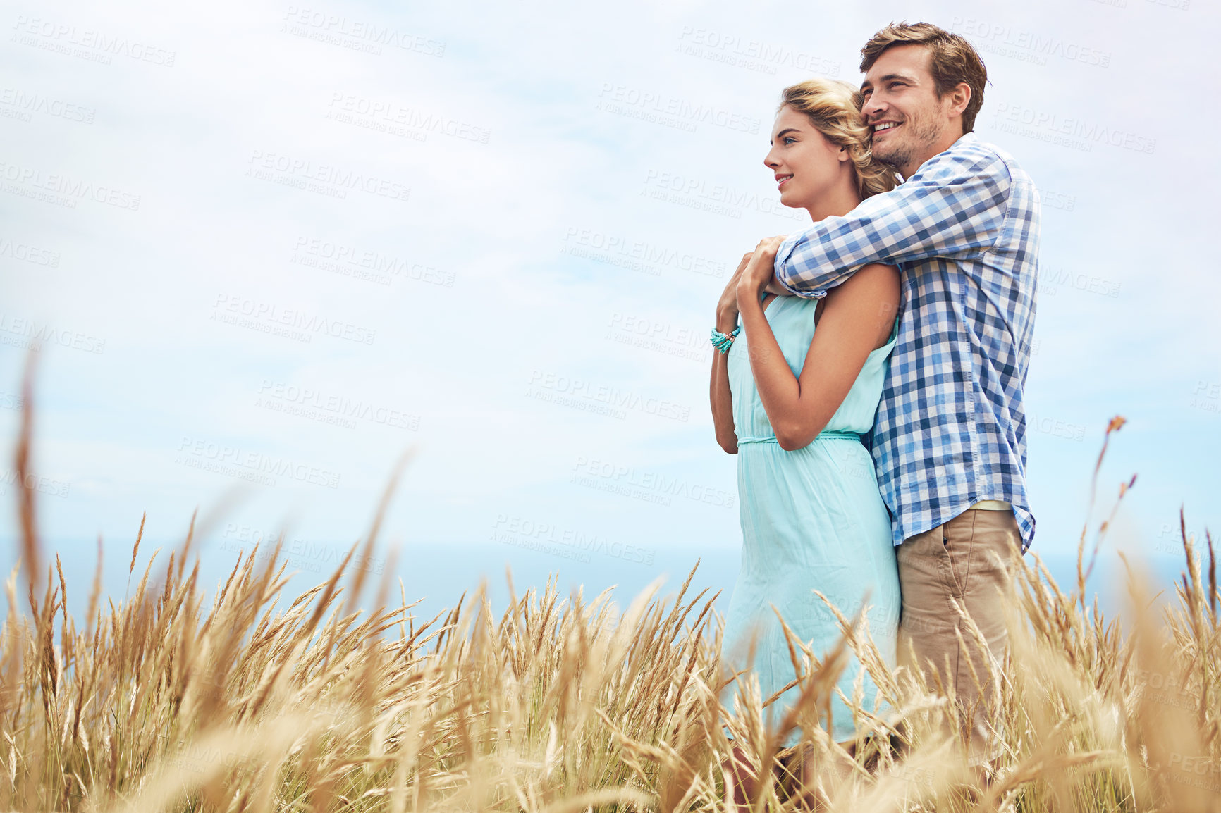 Buy stock photo Shot of a young couple in a field on a sunny day