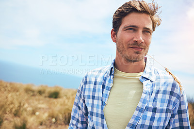 Buy stock photo Shot of a young man in a field on a sunny day