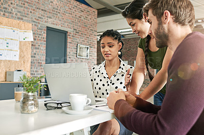 Buy stock photo Shot of a team of colleagues using a laptop together in a modern office