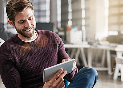 Buy stock photo Shot of a young man using a digital tablet in an office