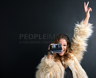 Buy stock photo Studio portrait of a young woman taking a photo against a dark background