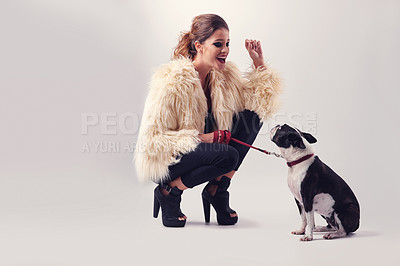 Buy stock photo Studio shot of a young woman posing with her dog against a grey background