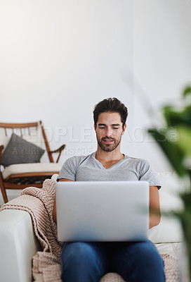 Buy stock photo Shot of a young man browsing the internet at home on a laptop