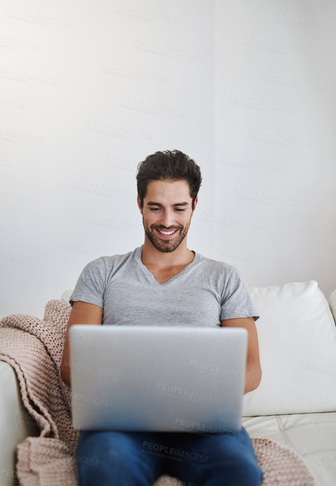 Buy stock photo Shot of a young man browsing the internet at home on a laptop