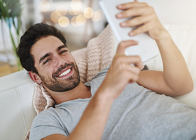 Buy stock photo Shot of a young man browsing the internet at home on a digital tablet