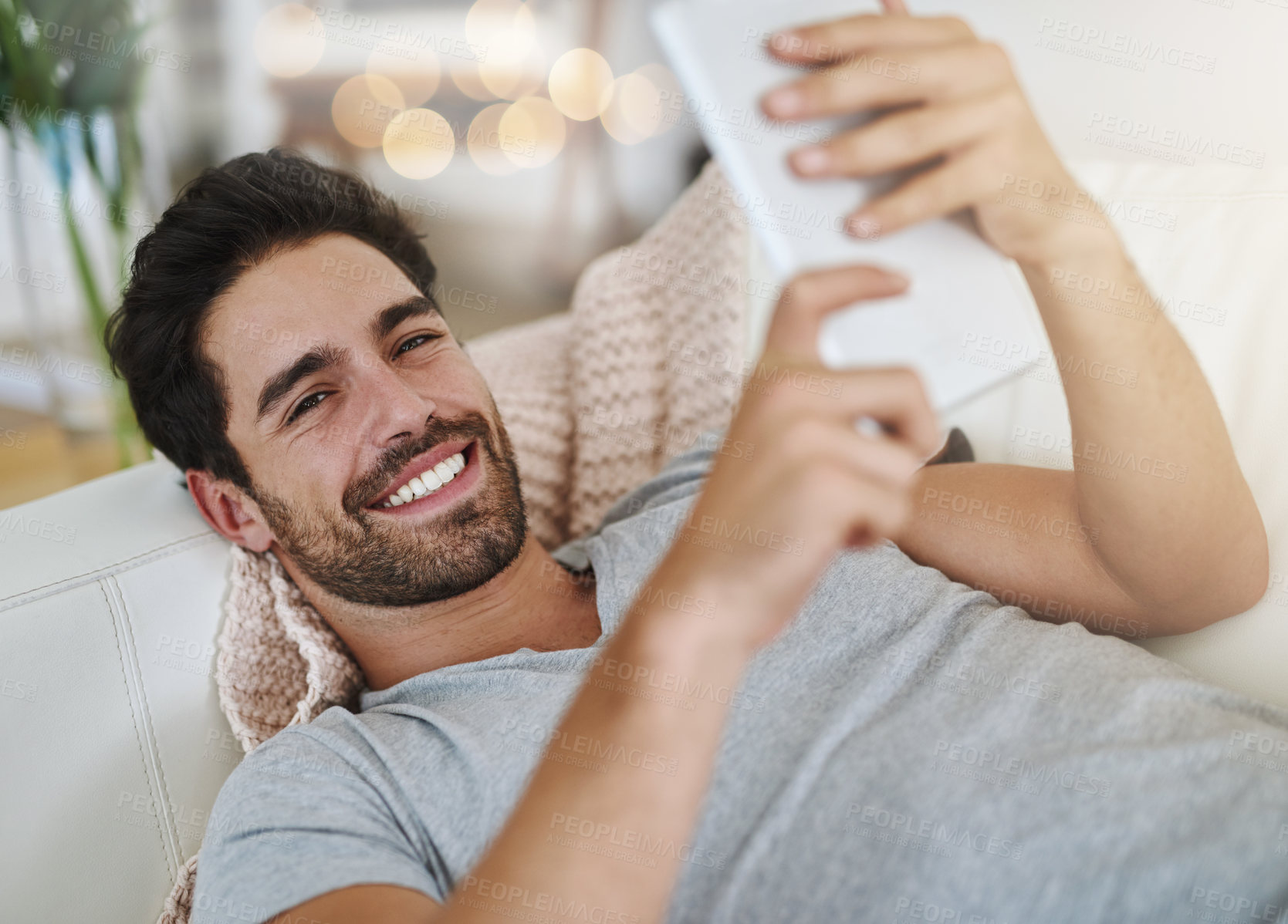 Buy stock photo Shot of a young man browsing the internet at home on a digital tablet