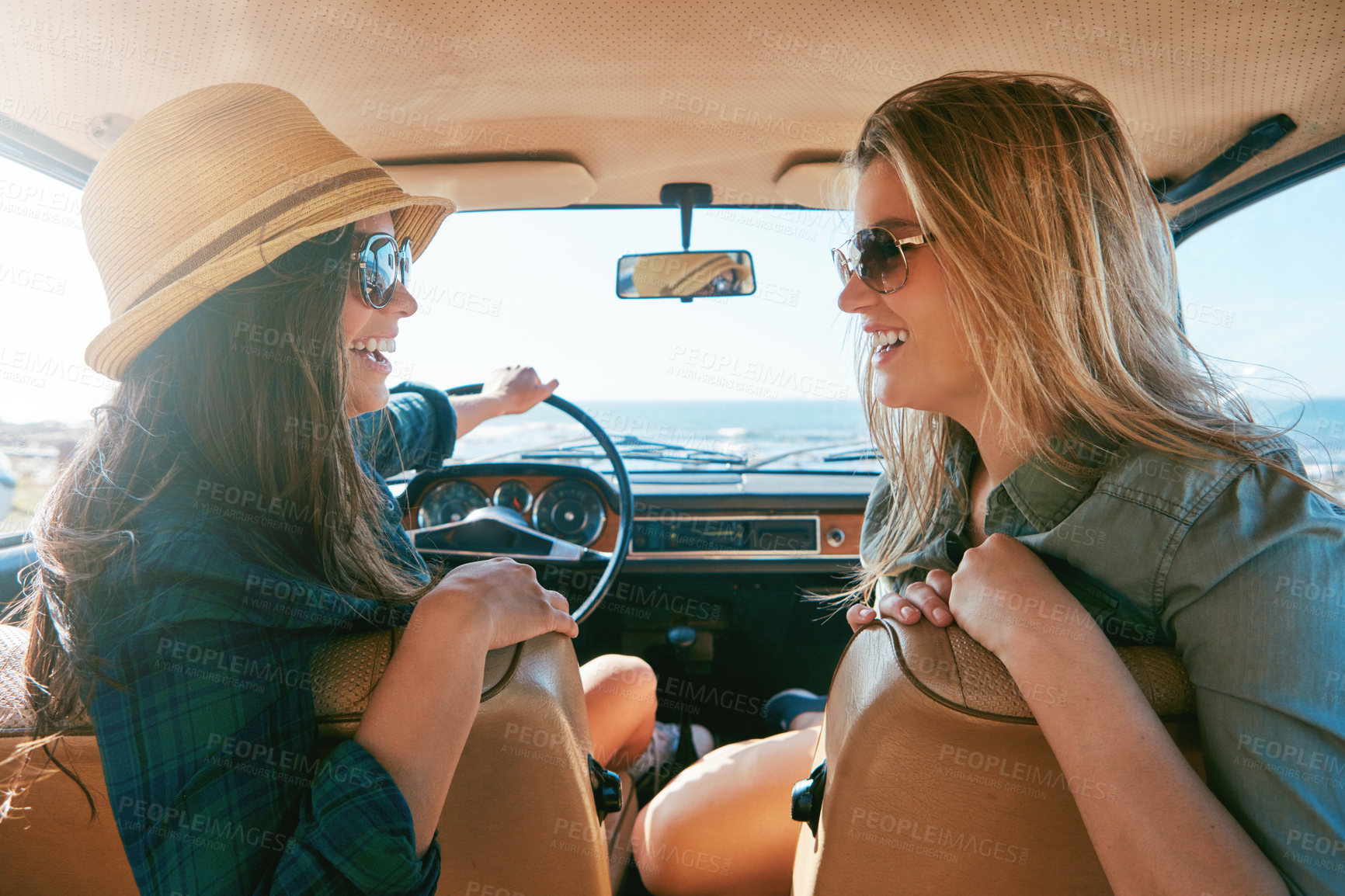 Buy stock photo Shot of two friends on a road trip near the ocean