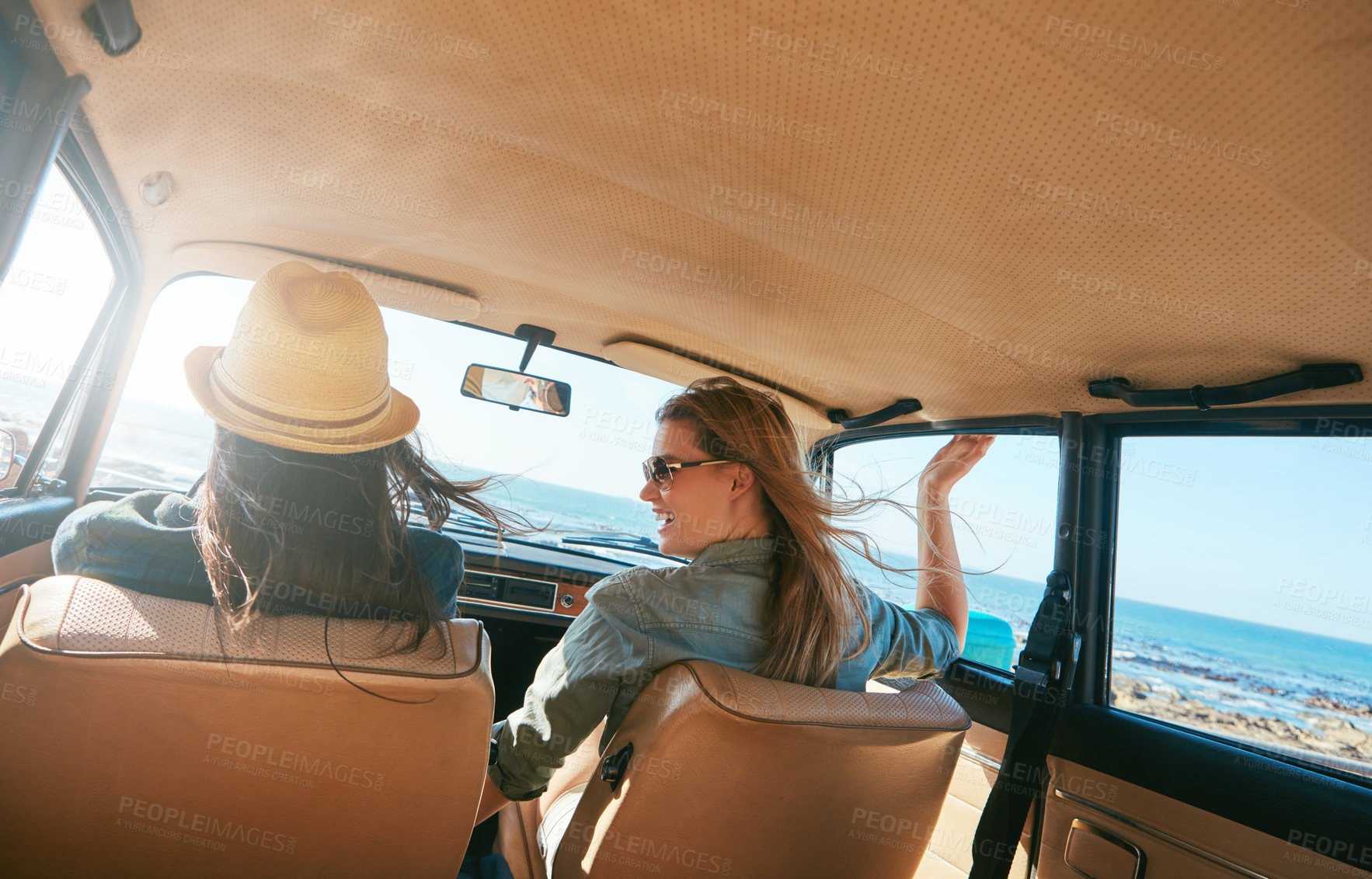 Buy stock photo Shot of two friends on a road trip near the ocean