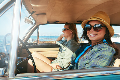 Buy stock photo Shot of two friends on a road trip near the ocean