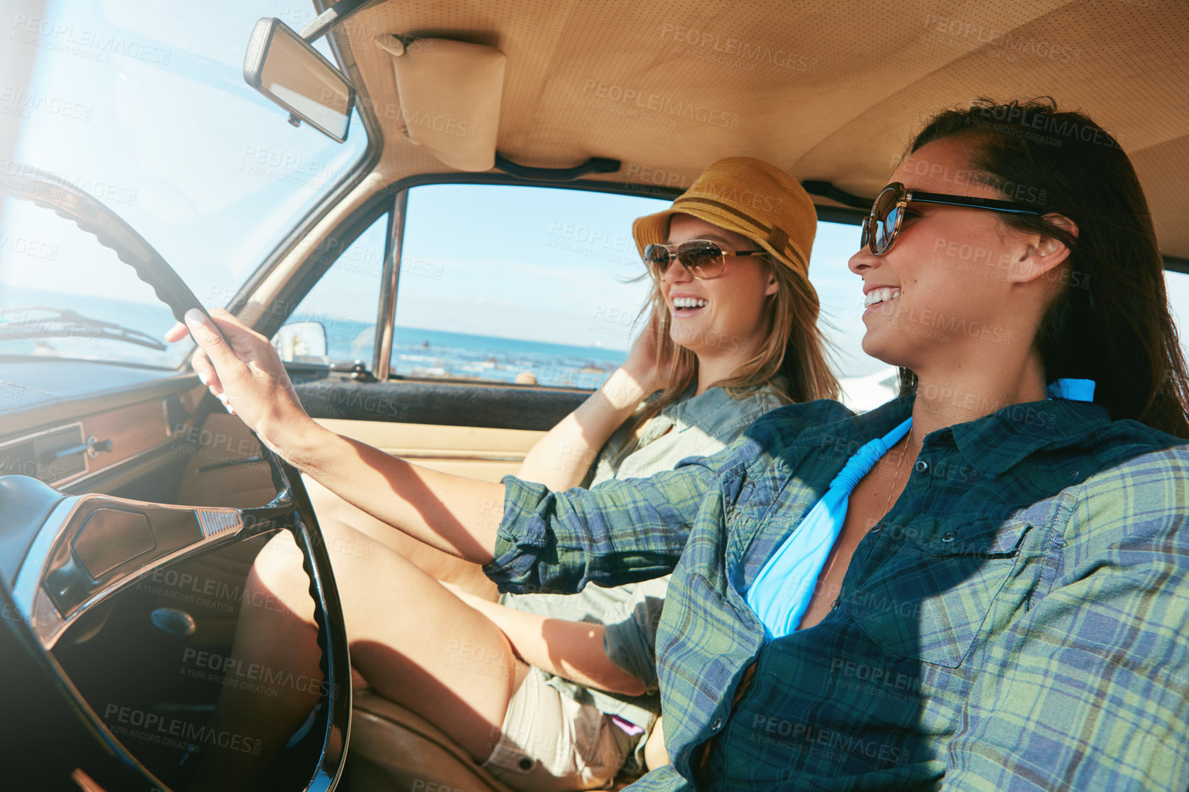 Buy stock photo Shot of two friends on a road trip near the ocean