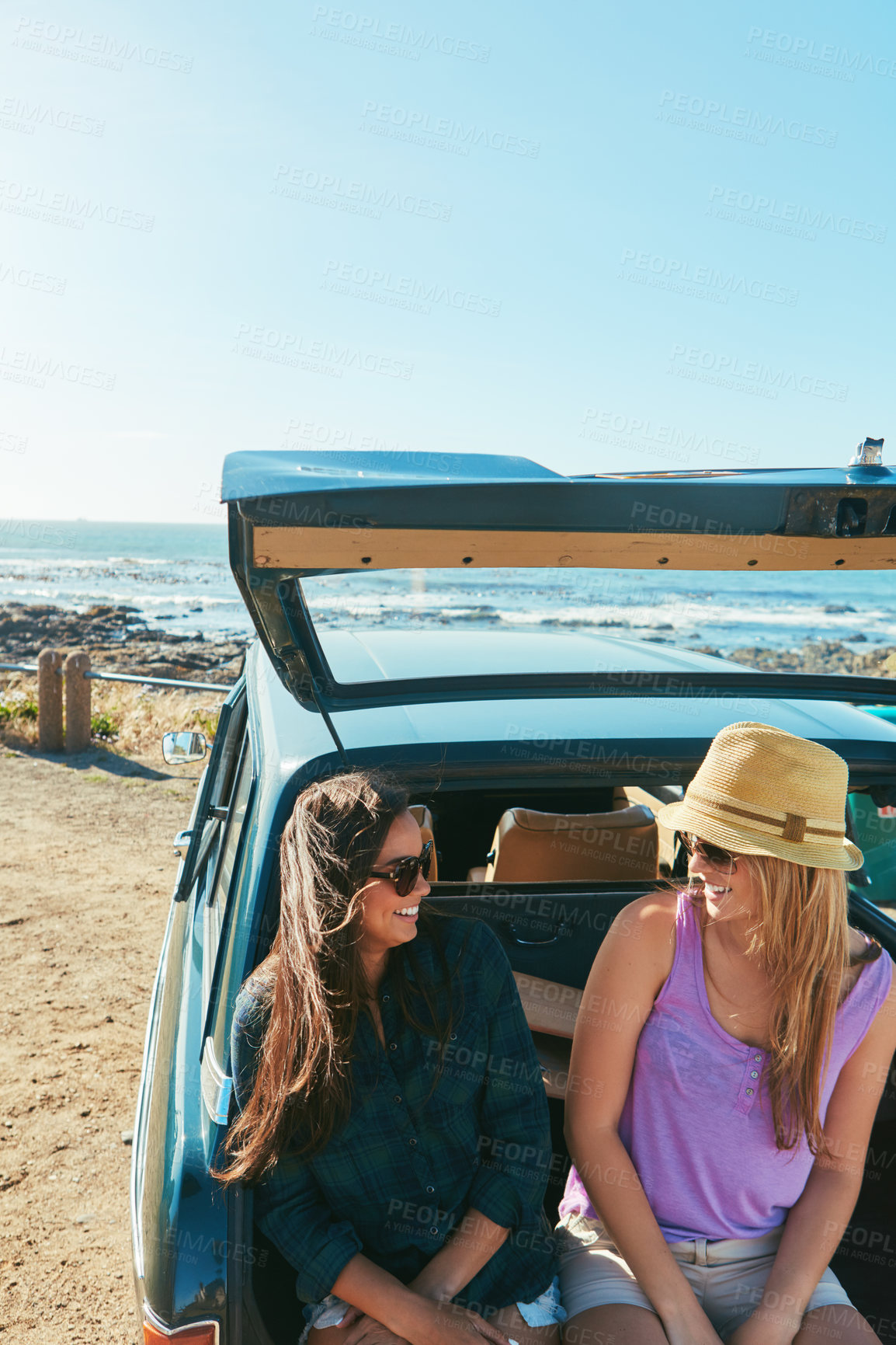 Buy stock photo Shot of two friends on a road trip near the ocean