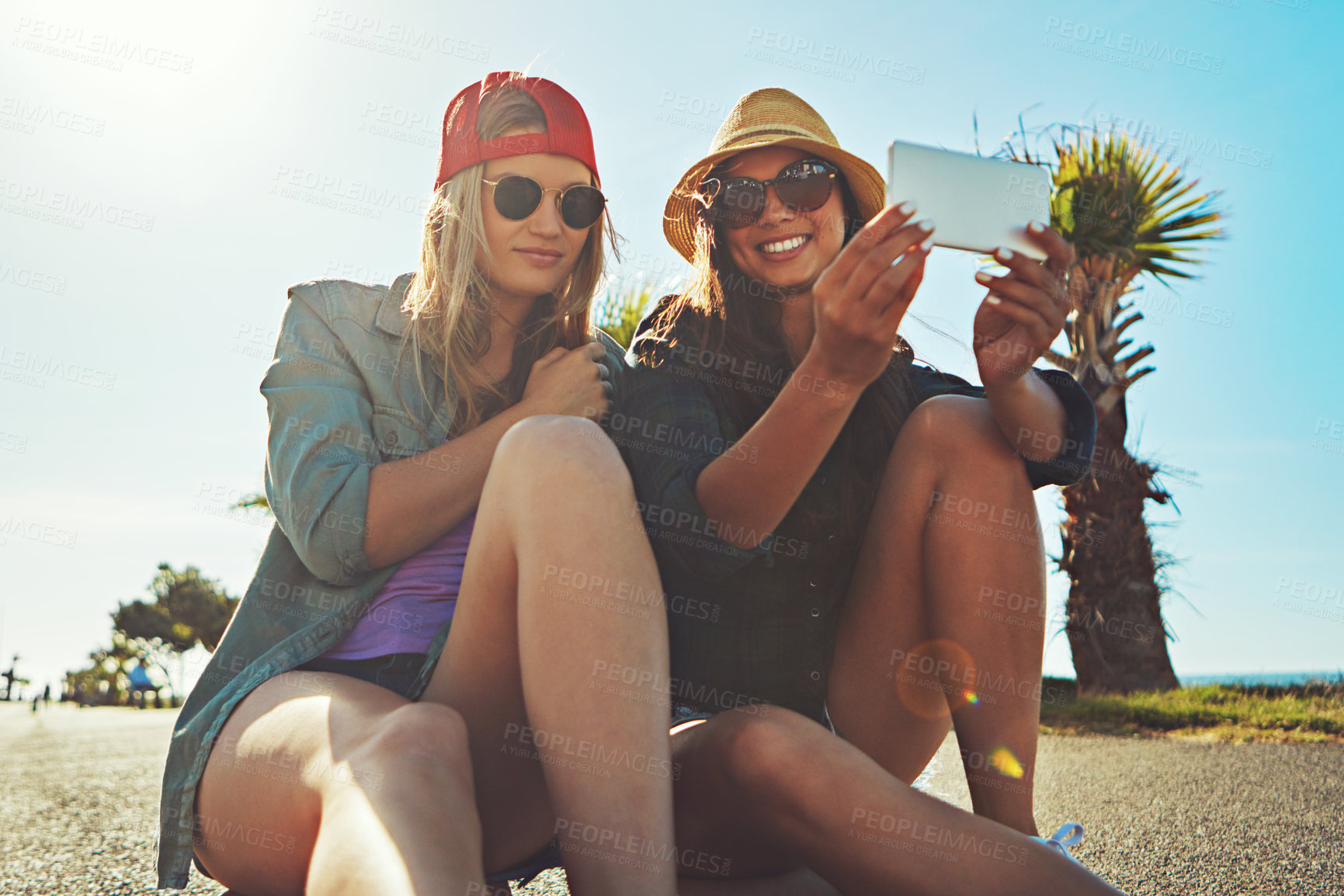 Buy stock photo Shot of two friends hanging out on the boardwalk with a skateboard