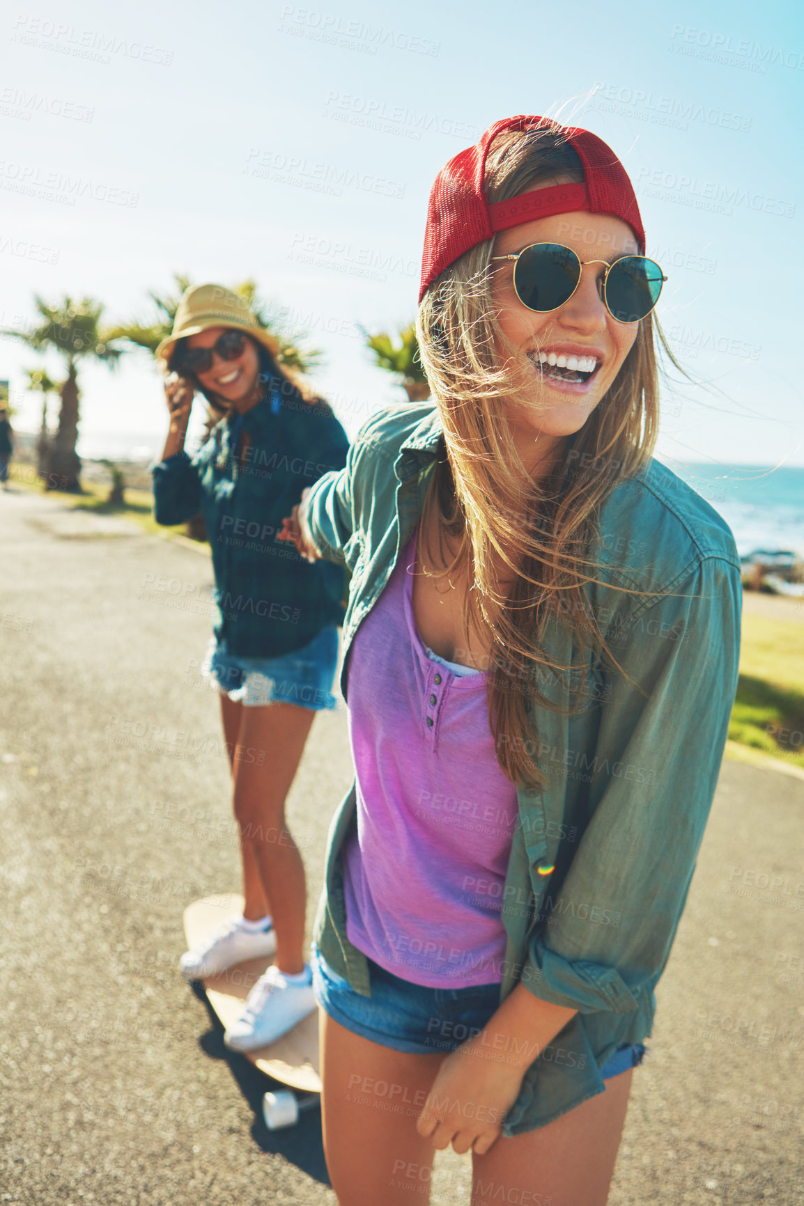 Buy stock photo Shot of two friends hanging out on the boardwalk with a skateboard