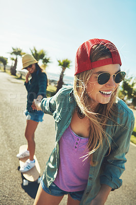 Buy stock photo Shot of two friends hanging out on the boardwalk with a skateboard