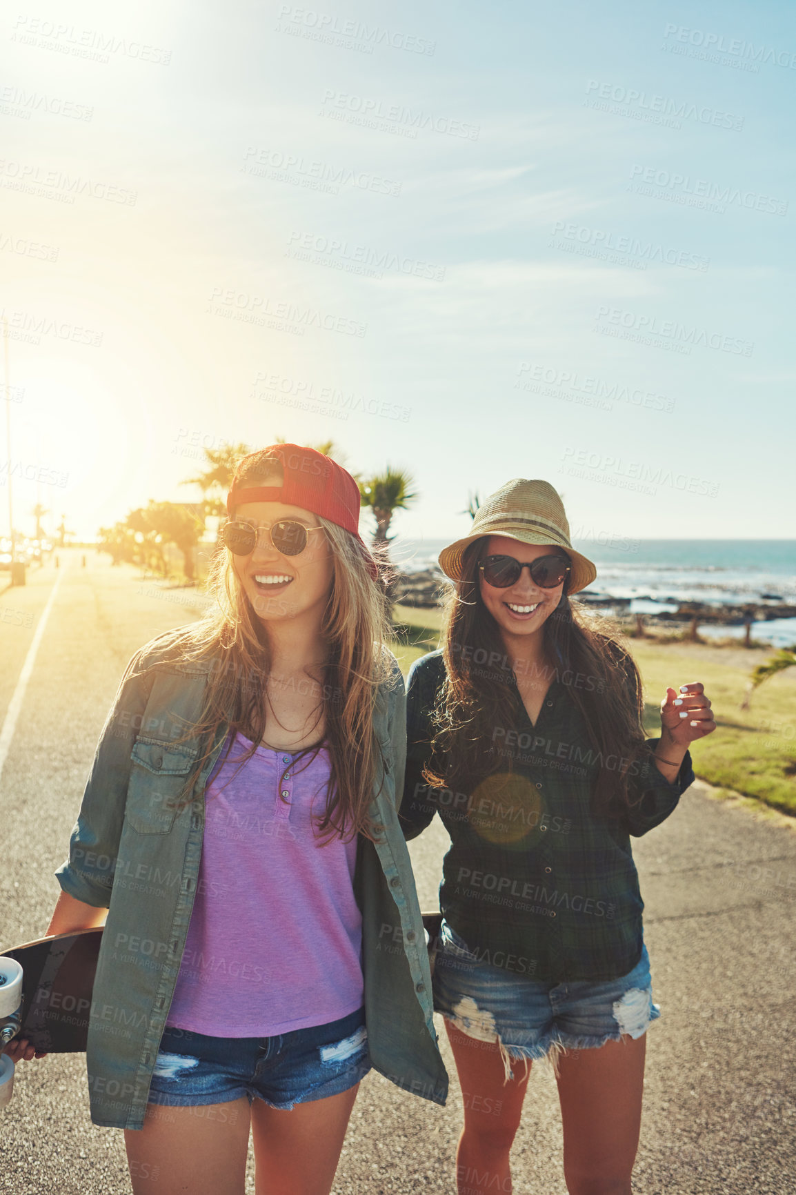 Buy stock photo Shot of two friends hanging out on the boardwalk with a skateboard