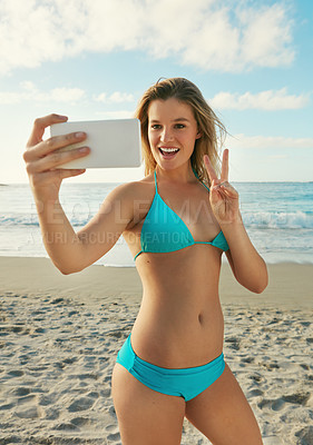 Buy stock photo Shot of a young woman taking a selfie while hanging out at the beach
