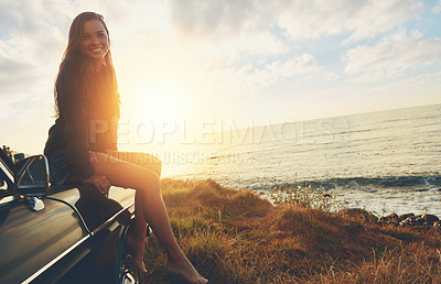 Buy stock photo Road trip, portrait and sunset with a woman at the ocean, sitting on her car bonnet during travel for freedom or escape. Nature, flare and mockup with a young female tourist traveling in summer