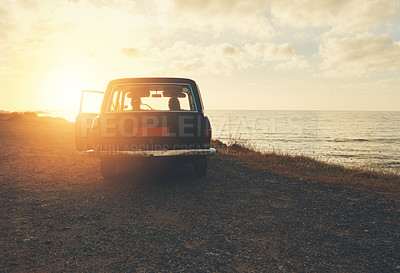 Buy stock photo Rearview shot of two friends on a road trip to the beach at sunset