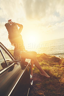 Buy stock photo Road trip, portrait and sunset with a woman at the coast, sitting on her car bonnet during travel for freedom or escape. Nature, lens flare and water with a young female tourist traveling in summer