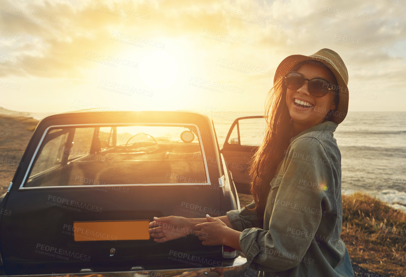 Buy stock photo Cropped portrait of a young woman on a road trip to the beach at sunset