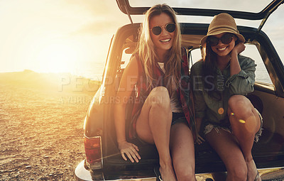 Buy stock photo Cropped portrait of two friends sitting in the trunk of a car while on a road trip