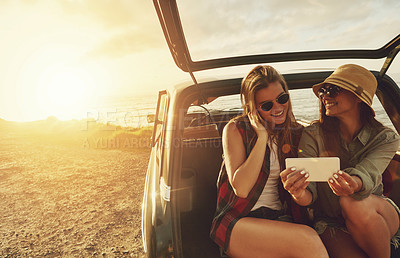 Buy stock photo Cropped shot of two friends taking a selfie while sitting in the trunk of a car