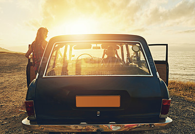 Buy stock photo Shot of two friends on a road trip to the beach at sunset 