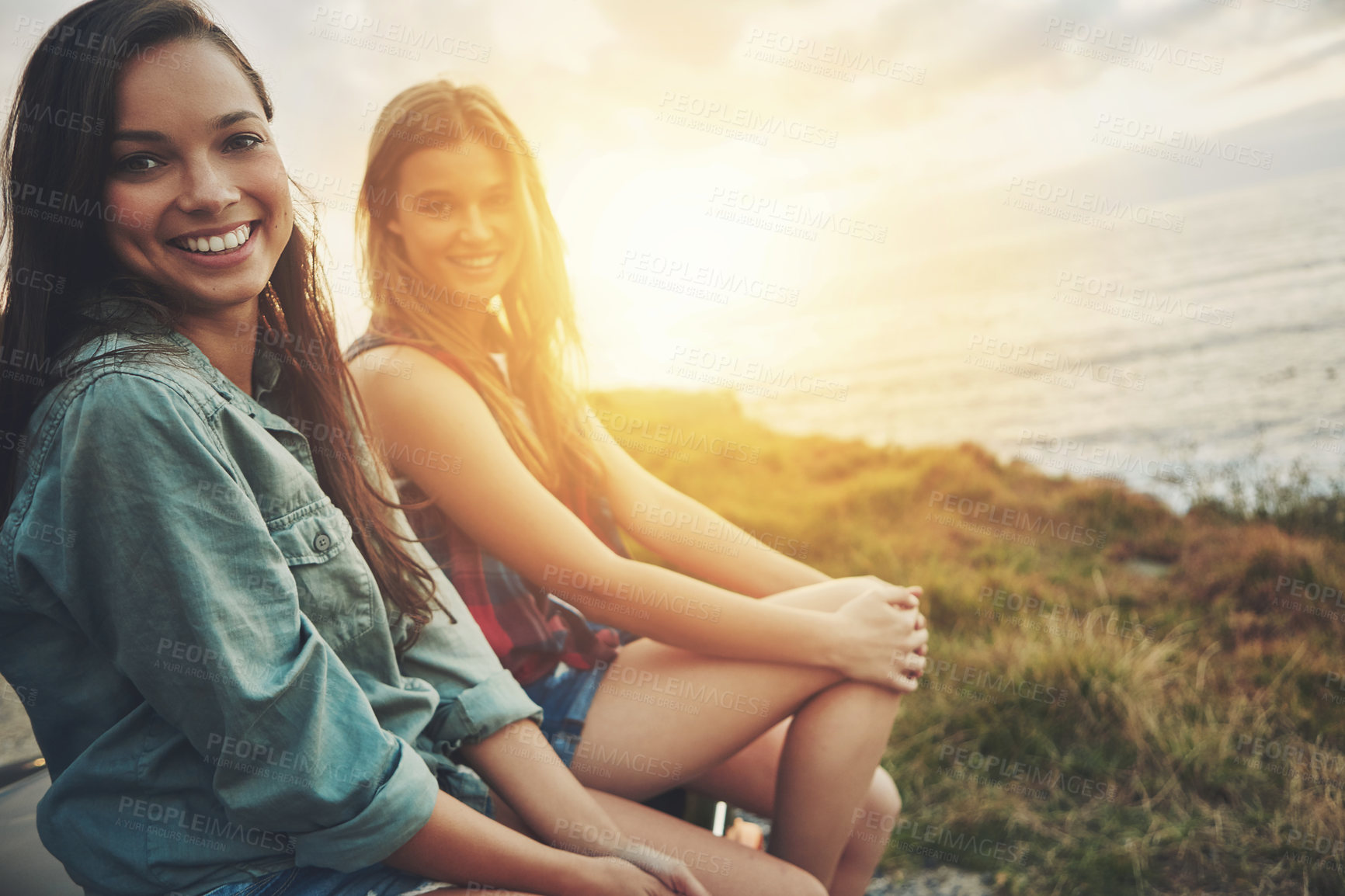 Buy stock photo Cropped portrait of two friends on a road trip to the beach at sunset