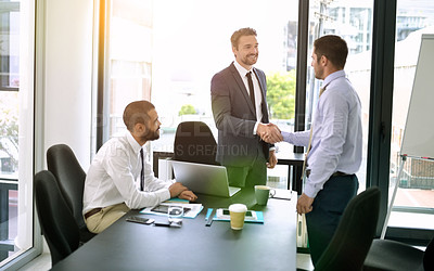 Buy stock photo Shot of colleagues shaking hands during a formal meeting in an office