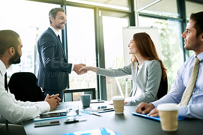 Buy stock photo Shot of colleagues shaking hands during a formal meeting in an office