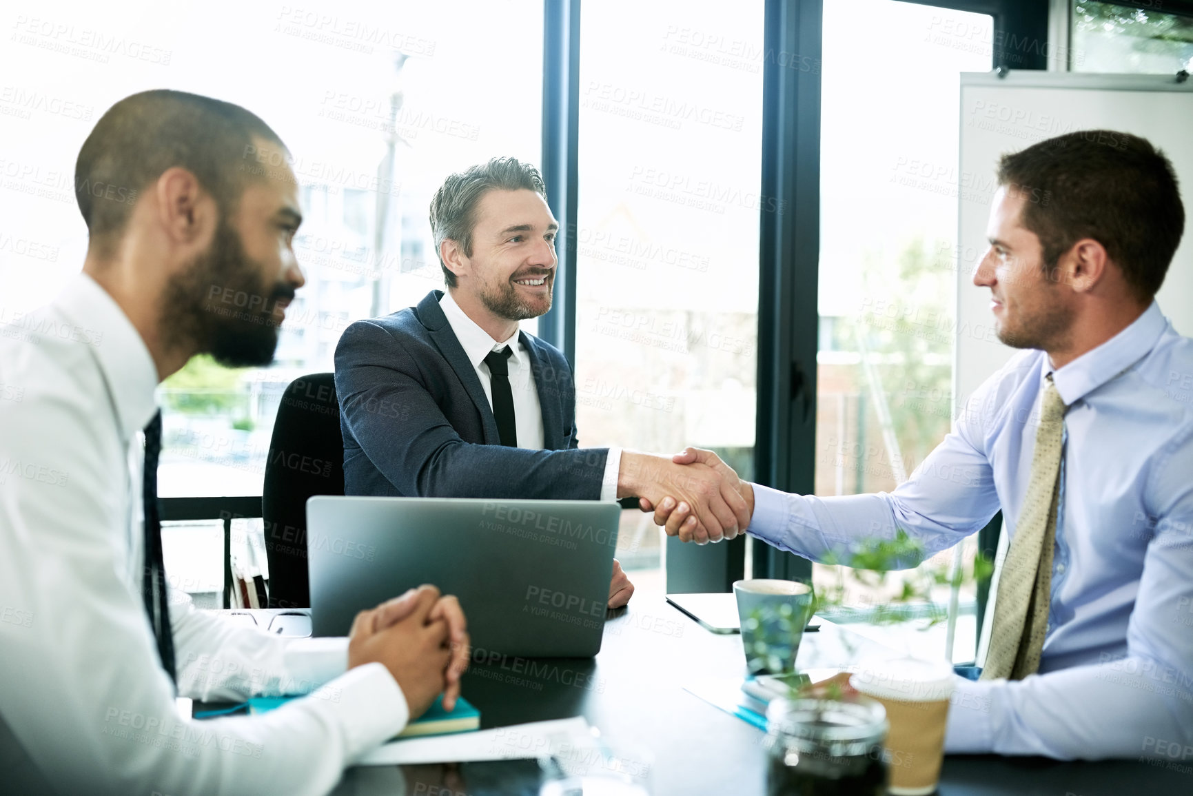 Buy stock photo Shot of colleagues shaking hands during a formal meeting in an office