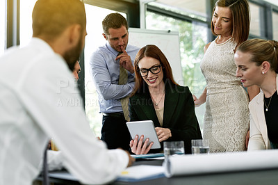 Buy stock photo Shot of a team of colleagues using a digital tablet together during a meeting in an office