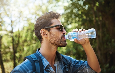 Buy stock photo Shot of a young man stopping for a drink of water while exploring the outdoors