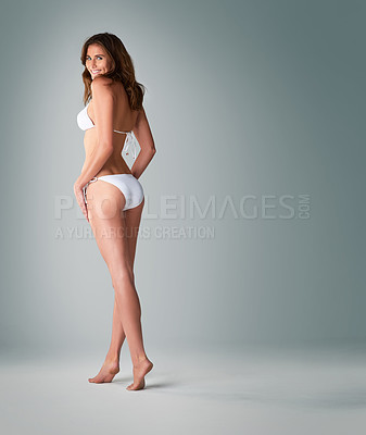 Buy stock photo Studio shot of a beautiful young woman in a bikini against a gray background