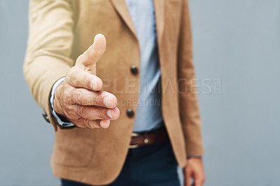 Buy stock photo Cropped shot of a businessman extending his arm to shake hands against a gray background