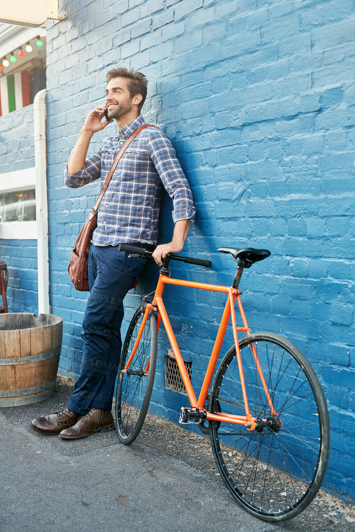Buy stock photo Bike, phone call and smile with business man on blue wall in city for morning commute to work. Contact, thinking and transportation with happy young employee talking on mobile for communication