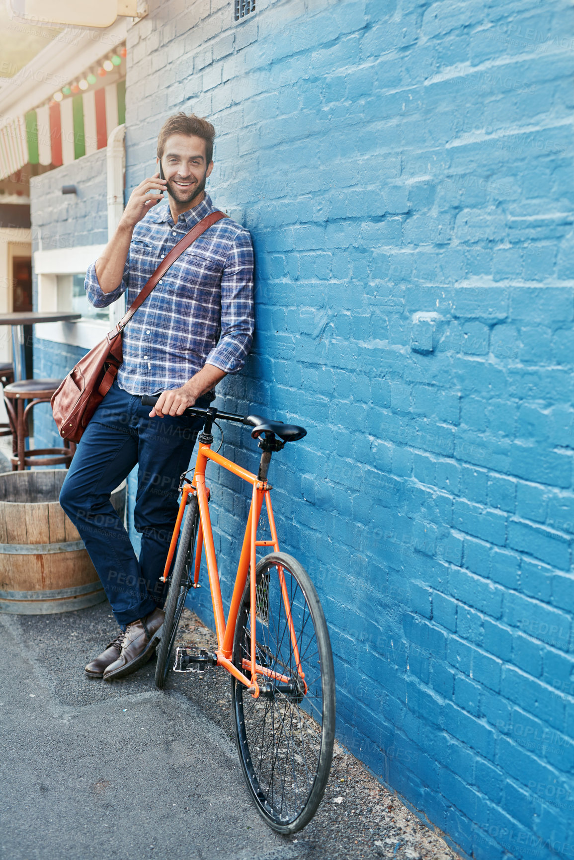 Buy stock photo Man, portrait and phone call outdoor by bicycle with communication, conversation and talking by brick wall. Person, face and happy with smartphone in city with bike for travel and commute on mockup
