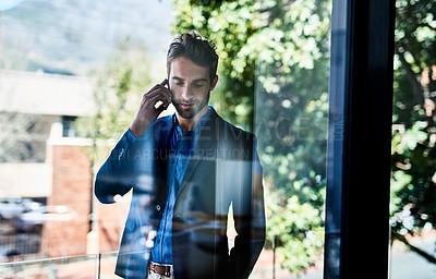 Buy stock photo Shot of a young businessman talking on the phone outside an office